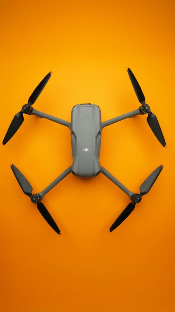 Top view of a sleek folding drone isolated on a vibrant orange background.