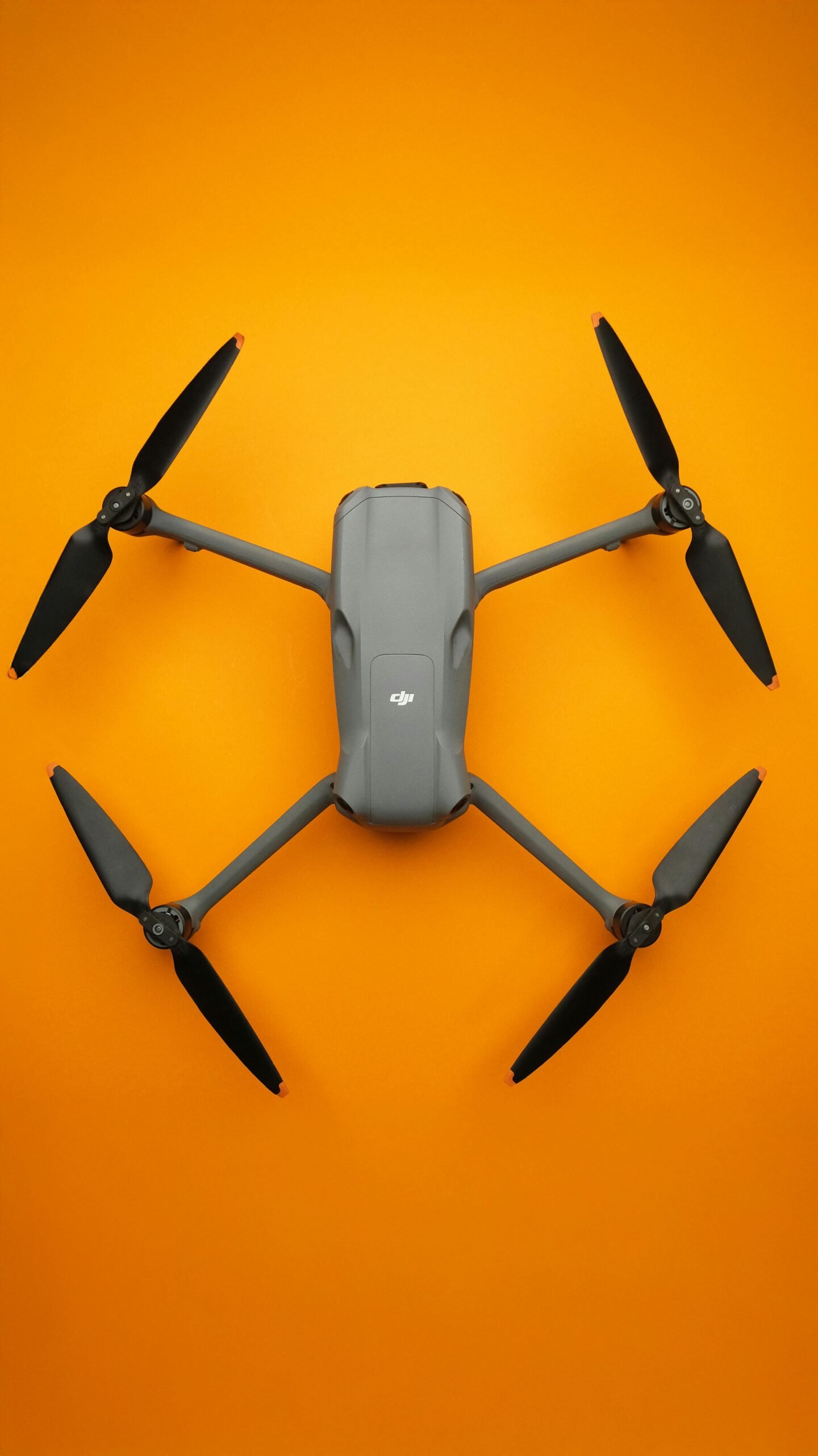 Top view of a sleek folding drone isolated on a vibrant orange background.